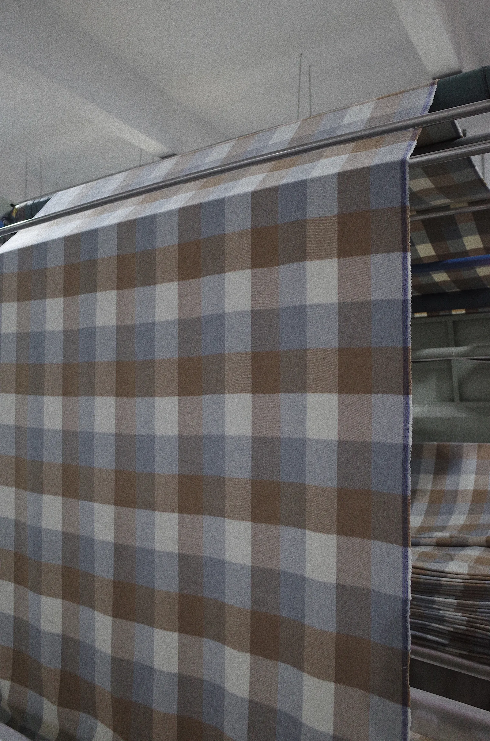 Grey and camel checked woolen fabric running through finishing