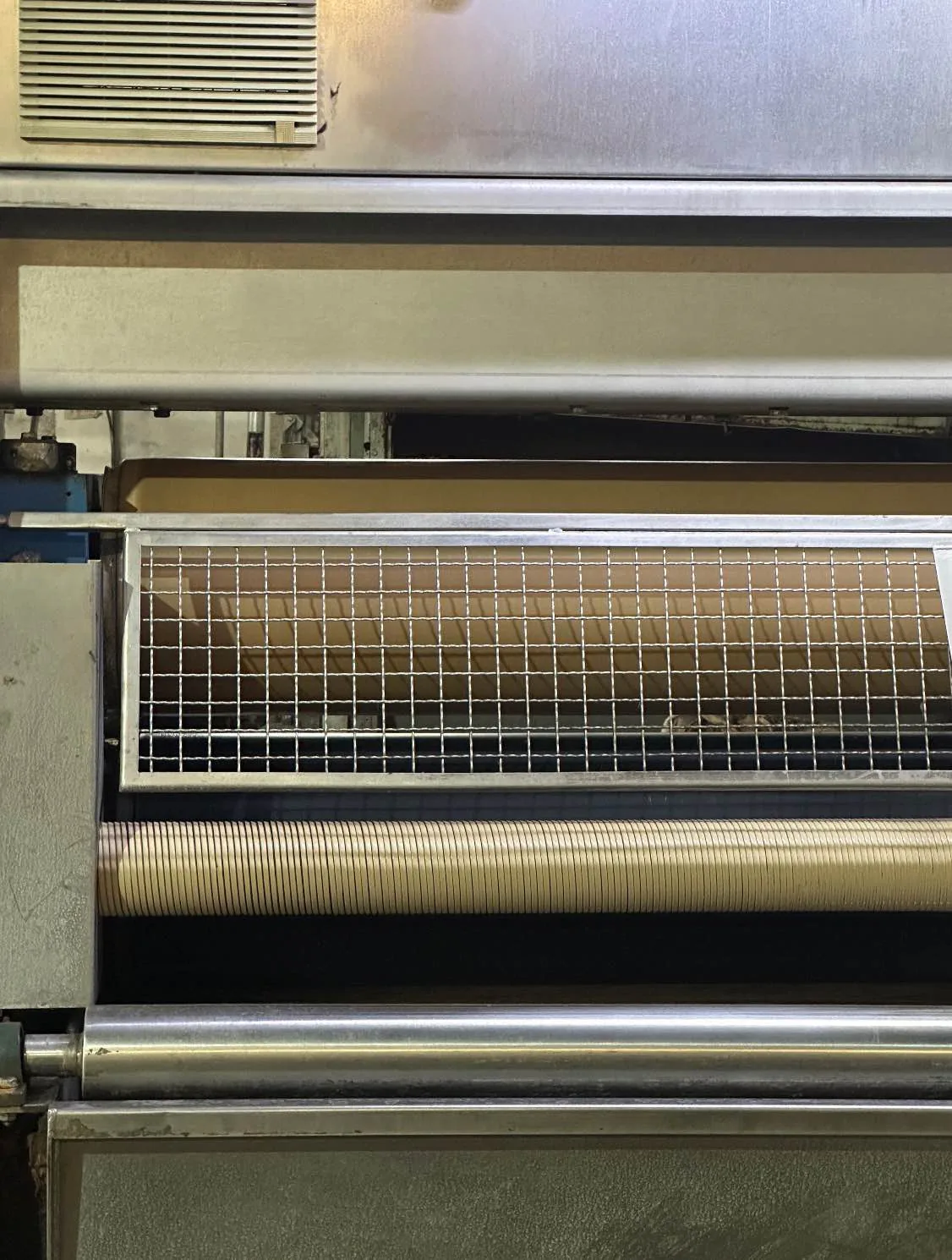 Woolen fabric moving through a guarded finishing machine