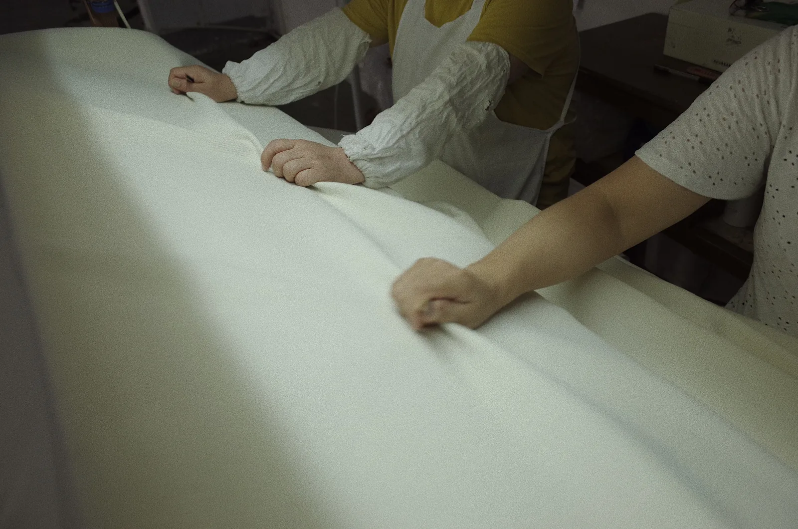 Fred Textile workers checking the surface of white fabric by hand