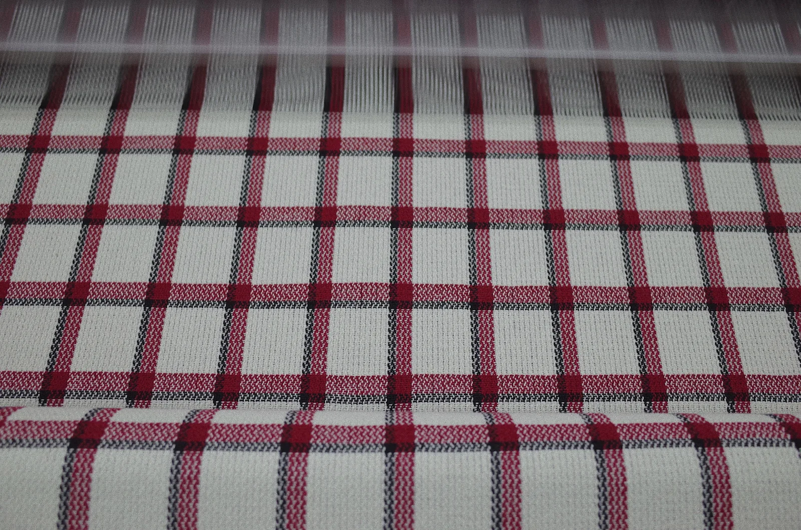 Red black and white check wool-blend fabric across the loom